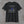 Black We Will Never Forget tee, back print: greyscale flag and skyline with the Twin Towers standing in blue
