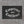 Competence over Confidence flag in white blackletter on black, hung flat against a concrete wall