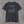 Charcoal We Will Never Forget tee, back print: greyscale flag and skyline with the Twin Towers standing in blue
